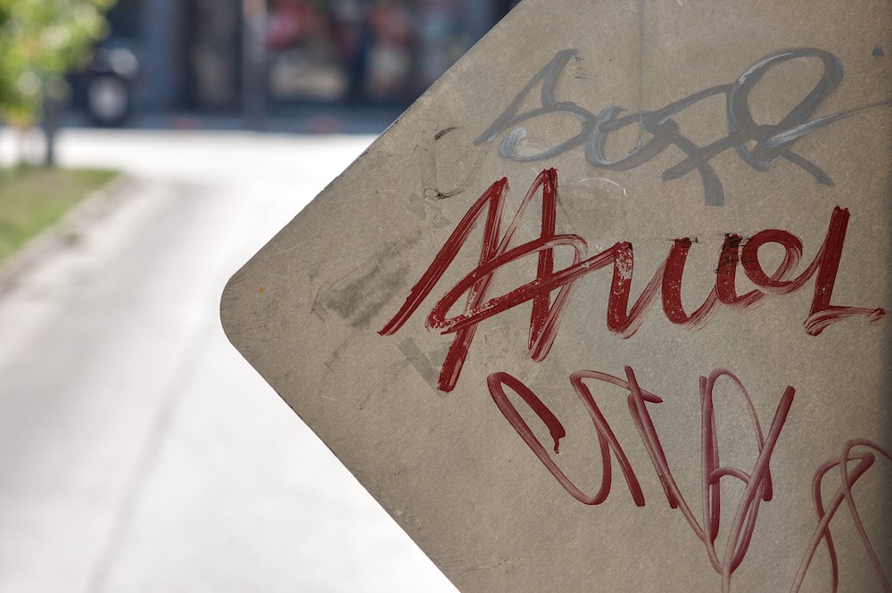 the back of a road sign with graffiti on it.