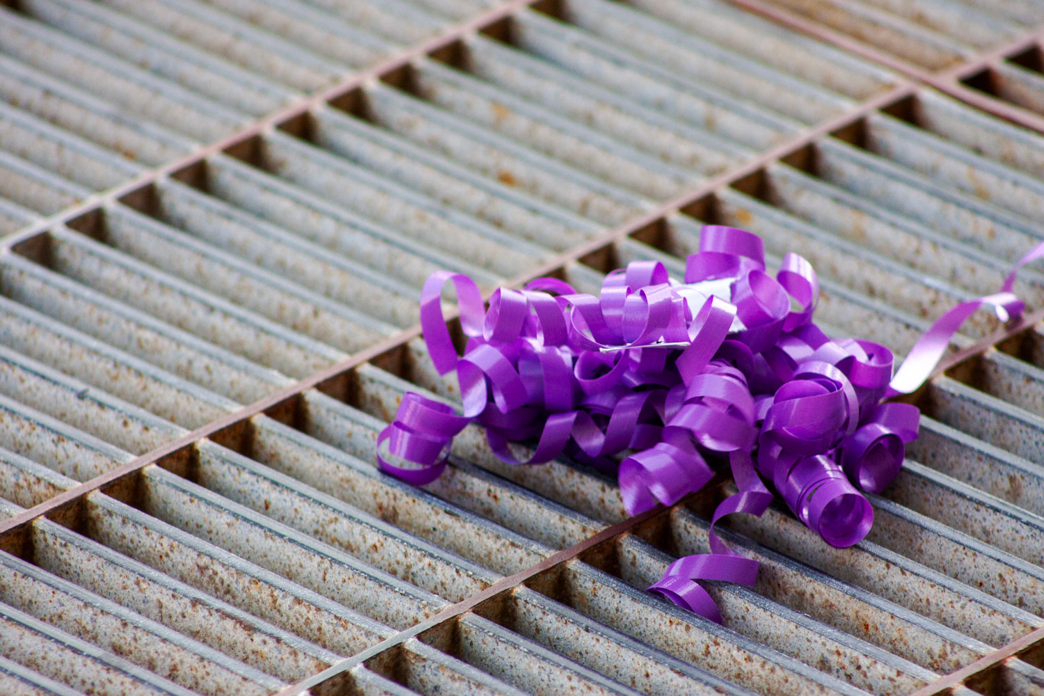 a purple ribbon on a metal grate on the street